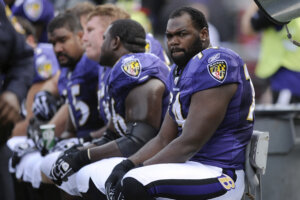 Michael Oher sits on the beach during the first half of an NFL football game