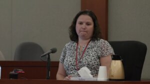 a woman wearing a floral shirt sits in front of a microphone