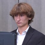 a young man in a suit testifies in court