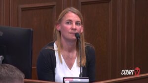 A woman speaks into a microphone while testifying in court