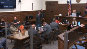 a defendant and attorneys sit in court
