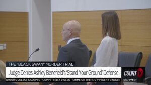 A woman stands next to her attorney in court