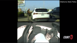 Dashboard camera video shows the back of a white vehicle and a man in handcuffs sitting in a separate vehicle