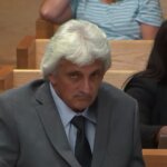 A man sits in a suit in court