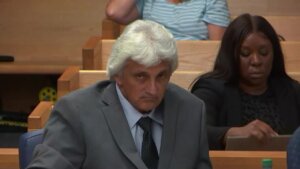 A man sits in a suit in court