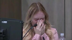 a woman holds her hands to her face as she cries in court