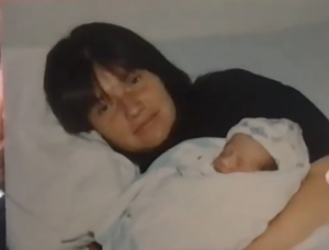 A smiling woman holds a baby