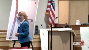 A woman points to a large display on an easel in court