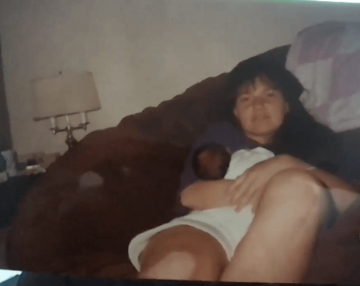 A woman sits on a couch holding a child