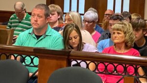 A family sits in the gallery of a courtroom