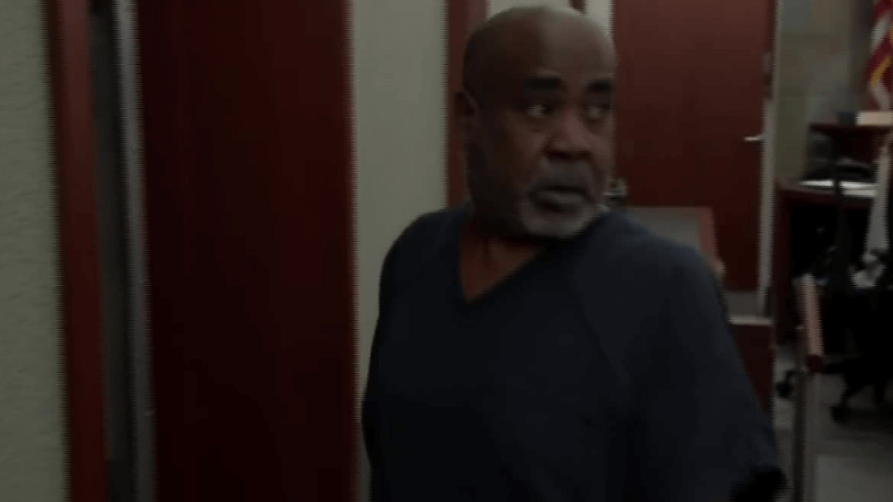 A man wearing a black shirt walks through a courtroom