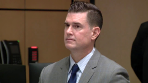 A man in a suit stands in court