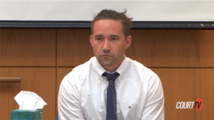 a man in a shirt and tie sits in court