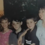 a smiling woman stands with children