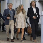 two women and a man walk out of a courthouse