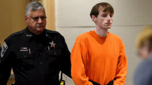 Logan Clegg appears in an orange jumpsuit and shackles