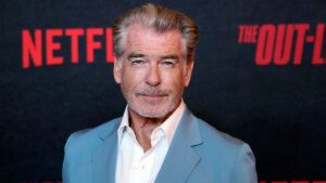 Pierce Brosnan stands in front of a Netflix background