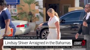 A woman in a white jumpsuit walks past the camera