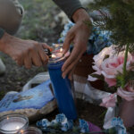 hands light a candle at a memorial