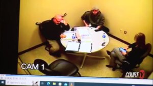 three people sit around a table in surveillance video