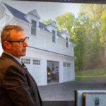 Witness testifies next to picture of a house