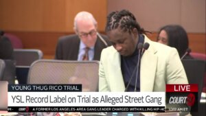 Young Thug sits in court wearing a white jacket