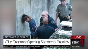 A woman rests her head against the wall as she's arrested