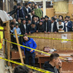 Hasidic Jewish students observe as law enforcement establishes a perimeter