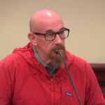 A man in a red shirt testifies in court