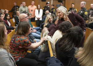 Group of people stand with their hands together.