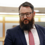 A man with a beard stands in court