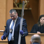 detective holds a piece of evidence in court