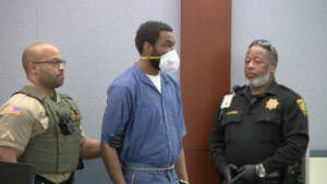 Deobra Redden wears a mask and shackles in court