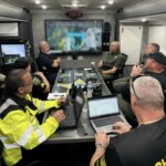 people sit around a table in a command center