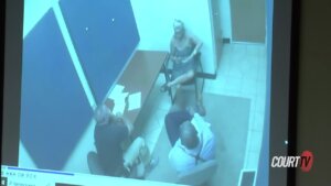 Three people sit in an interview room seen on surveillance video