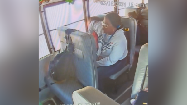 still from surveillance video shows school bus aide elbowing child