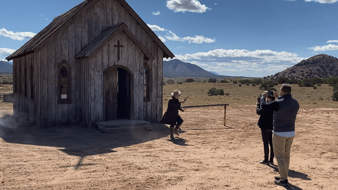 Alec Baldwin, in costume, fires a gun as he exits a church