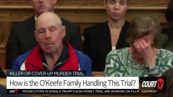 man and woman sit in court, woman covers face with hands
