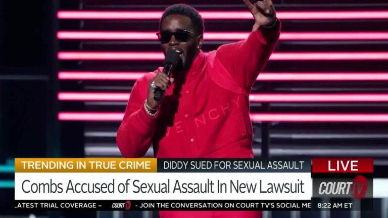 Diddy in a red suit and sunglasses on stage.