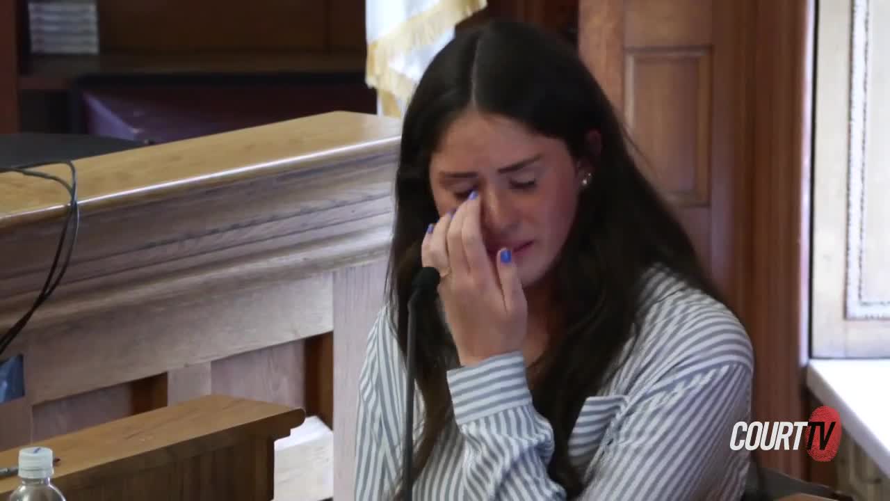 Female witness with long dark hair cries on the stand.