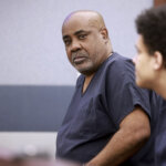 A man in a prison jumpsuit listens in court.