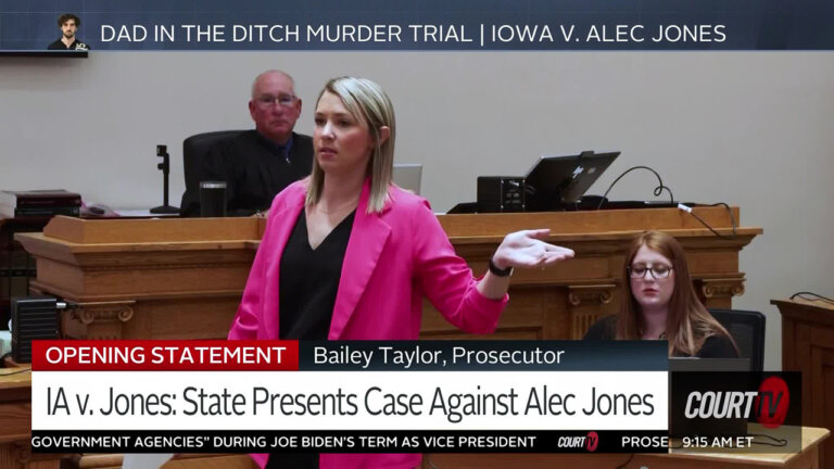 Young blonde female attorney in a hot pink blazer and black blouse delivers an animated argument.