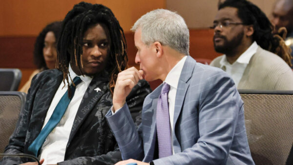 A man whispers to a second man in court