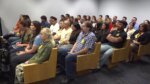 Packed gallery of people sitting inside a courtroom