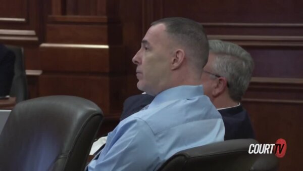 Middle-aged defendant in a blue button-down shirt listens in court.