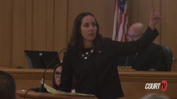 Female attorney dressed all in black delivers an argument while gesticulating.