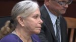 close up of elderly, grey-haired female defendant in a purple prison jumper