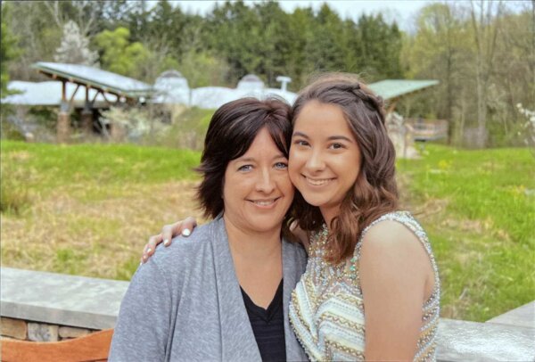 Two women embrace while smiling for a photo