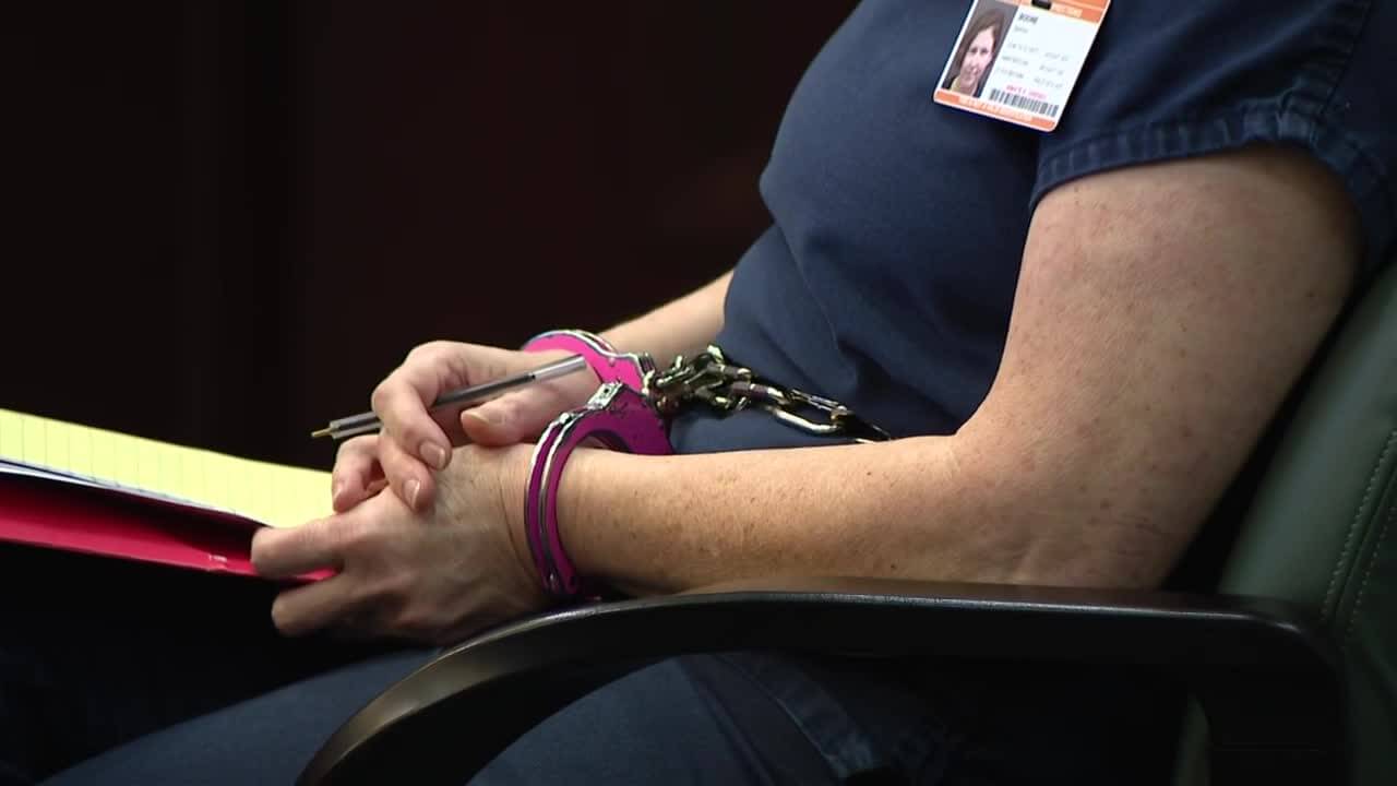 a woman holds a pen in handcuffs