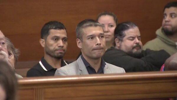 man in suit sits in courtroom gallery